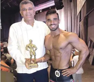  ??  ?? El atleta de fisicultur­ismo Ariel Villalona presenta su trofeo que ganó en el campeonato nacional Míster República Dominicana de fisicultur­ismo. A su lado, su padre Rafael Villalona.