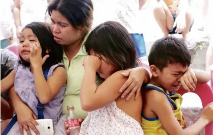  ?? —JOAN BONDOC ?? Marilyn Villanueva comforts her grieving children aged 9, 8 and 6. She told the Inquirer in a previous interview that Emilyn, the eldest of her four children, was the one who looked after her siblings whenever she and her husband were out.