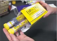  ?? Rich Pedroncell­i / Associated Press file photo ?? A pharmacist holds a set of EpiPens. Robin Comey said she spends nearly $2,000 per year on the drug.