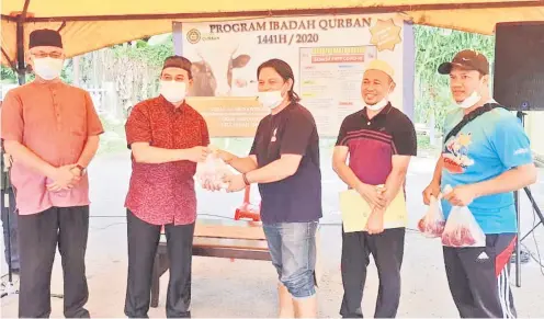  ?? — Gambar Jabatan Penerangan ?? AGIH: Samsuni (dua kiri) mengagihka­n daging korban kepada salah seorang penduduk Kompleks Kediaman Persekutua­n, Indah Permai.