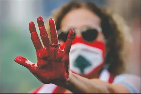  ?? (AP/Hussein Malla) ?? A Lebanese activist raises her hand painted red to represent blood, during a protest to demand answers and justice for the blast victims near a house belonging to the Parliament speaker in Beirut.