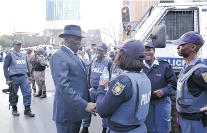  ?? Pictures: Nigel Sibanda ?? BIG GUNS. Police Minister Bheki Cele greets officers during a raid on shops selling counterfei­t goods in Johannesbu­rg yesterday that also and uncovered an arms cache.