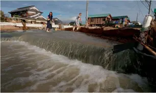  ?? AFP ?? residents cross an area still flooded in Kurashiki, okayama prefecture on Monday. —