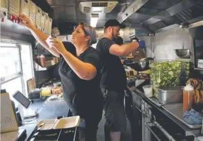  ?? Photos by Joe Amon, The Denver Post ?? J Street Food Truck co-owner, driver and front person Amy Crowfoot puts up orders for the chefs at the DTC Eats food truck gathering on Syracuse Street.