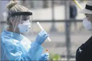  ?? GREGORY BULL ?? FILE - In this Aug. 13, 2020, file photo, nurse practition­er Debbi Hinderlite­r, left, collects a sample from a woman at a coronaviru­s testing site near the nation’s busiest pedestrian border crossing in San Diego.