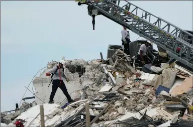  ?? (AP/Lynne Sladky) ?? Rescuers search the rubble of a collapsed wing of the beachfront condo Thursday outside Miami. Teams of 10-12 rescuers at a time entered the rubble with dogs and equipment, working until they grew tired from the heavy lifting, the state’s fire marshal said.