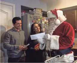  ?? NICOLE NERI/THE REPUBLIC ?? Santa, his elves, and the 100 Club of Arizona give sports tickets to Justin Lopez and his wife, Sara, on Friday in Goodyear.