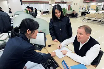  ??  ?? Le 29 novembre 2019, au Centre de services du commerce internatio­nal de Yiwu (province du Zhejiang), un Britanniqu­e consulte des employées.