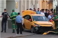  ?? (Reuters) ?? PEOPLE GATHER around the damaged taxi in central Moscow yesterday.