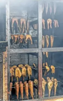  ??  ?? Fish suspended above the chippings in a modern smokehouse. Today, the method is used mainly to impart a smoky flavour, rather than to preserve the fish.