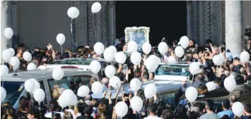 ?? — AFP ?? People carry white balloons as a child victim’s portrait is displayed following a funeral ceremony on Tuesday in Palermo for nine members of a single family who drowned when their home was engulfed in water following devastatin­g floods.