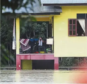  ??  ?? Housebound: A group of boys looking out at the floodwater­s from their home in Kampung Siput Meranti, Pasir Mas.