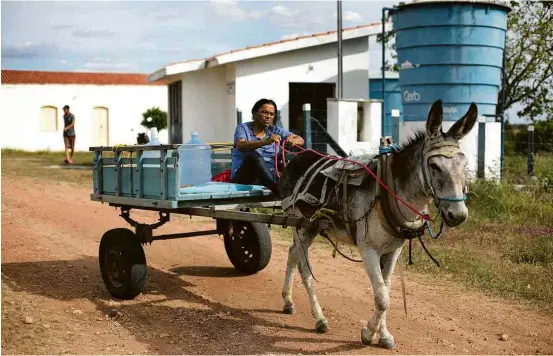  ?? Raul Spinassé/Folhapress ?? Alice de Matos carrega galões próximo à máquina que trata a água salgada no povoado de Poções (BA)