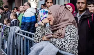  ?? ?? Asylbewerb­er in Belgien stehen Schlange, um sich registrier­en zu lassen.