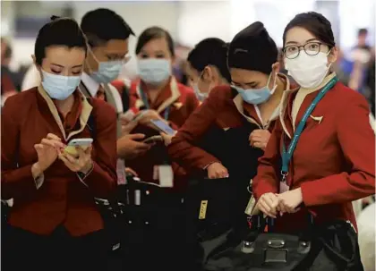  ?? MARIO TAMA/GETTY ?? A flight crew wearing protective masks stands in the internatio­nal terminal after arriving on a flight from Hong Kong at LAX on Friday.