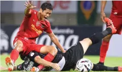  ??  ?? Bangkok United midfielder Pokklaw Anan, left, is fouled by a Port player.