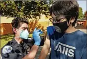  ?? Al Seib Los Angeles Times ?? AARON DELGADO, 16, receives a COVID vaccine from EMT Brandon Jaramillo in Arleta this month.