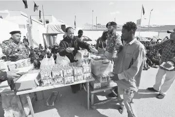  ??  ?? An African migrant receives food at a detention camp in Tripoli, Libya. — Reuters photo