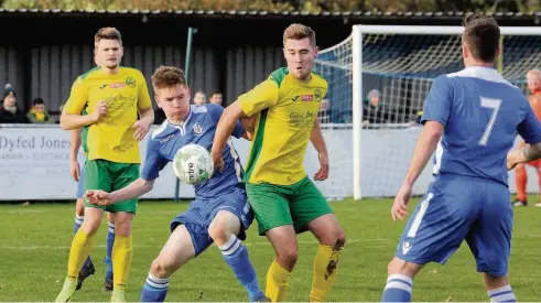  ??  ?? Llangefni Town defender Cai Powell Roberts (blue) tussles with Caernarfon Town striker Cory Williams. Picture: DAI SINCLAIR