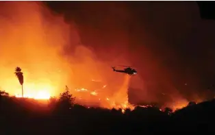  ?? PHOTOS BY GREGORY BULL/ASSOCIATED PRESS FILE PHOTO ?? A helicopter drops water over a wildfire in December 2017 in Bonsall, Calif. Environmen­tal groups have been arguing in California courts that developers are not fully considerin­g the risks of wildfire and choked evacuation routes when they plan housing developmen­ts near fire-prone areas.