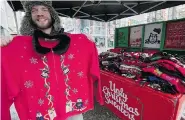  ?? JONATHAN HAYWARD/The Canadian Press ?? Stephen Peever holds up an ugly Christmas sweater on
Granville Street in downtown Vancouver on Dec. 5.