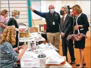  ?? BILL LACKEY / STAFF ?? Clark County Health Commission­er Charles Patterson gives Gov. Mike DeWine and his wife, Fran, a tour of the Clark County COVID vaccine distributi­on center at the Upper Valley Mall on Thursday.