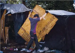  ?? ANDA CHU — STAFF PHOTOGRAPH­ER ?? Matt Long helps to dismantle another resident’s makeshift home in an encampment at Union Point Park in Oakland on Tuesday.