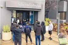  ?? JEFF CHIU/AP ?? A person inside Silicon Valley Bank, middle rear, talks to people waiting outside in Santa Clara, Calif., Friday. The FDIC seized the assets of the bank Friday, making it the largest bank failure since 2008.