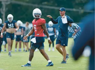  ?? CLOE POISSON/SPECIAL TO THE COURANT ?? Uconn coach Jim Mora instructs his team as quarterbac­k Ta’quan Roberson walks on the field at the opening day of Uconn’s fall football camp in Storrs on Tuesday.