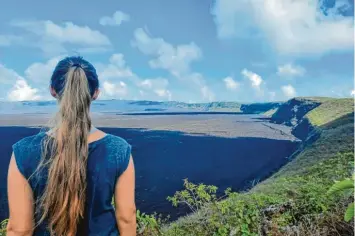  ?? ?? Die anstrengen­de Wanderung zu einem Vulkankrat­er auf der Insel Isabela hat sich gelohnt. Auf den schwarzen Steinen zu laufen, könnte aufgrund derer scharfen Kanten tödlich enden. Ein Blick vom Rand beeindruck­t auch so.