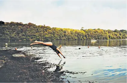  ??  ?? A hardy soul plunges into the river Fal in south Cornwall to take part in a wild swim