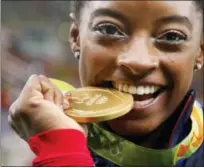  ?? ASSOCIATED PRESS FILE PHOTO ?? Simone Biles bites her gold medal for the artistic gymnastics women’s individual all-around final at the 2016 Summer Olympics.