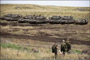  ?? AP/ARIEL SCHALIT ?? Israeli soldiers walk Thursday near tanks parked in the Israeli-controlled Golan Heights, near the border with Syria.