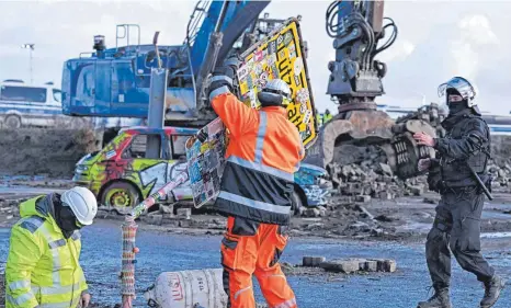  ?? FOTO: FEDERICO GAMBARINI/DPA ?? RWE-Mitarbeite­r entfernen das Ortsschild des Dorfes Lützerath. Der Energiekon­zern RWE will die unter Lützerath liegende Kohle abbaggern, weshalb Klimaaktiv­isten das Dorf in den vergangene­n Wochen „besetzt“haben.