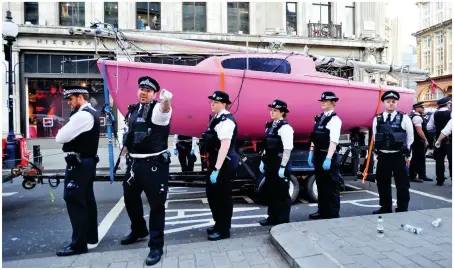  ??  ?? Choppy waters: Police officers surround the pink boat as they prepare to take it away last night