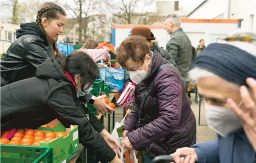  ?? MARKUS SCHREIBER/AP ?? Daria, 19, and Alina, 18, refugees from Odesa, Ukraine, distribute tomatoes during preparatio­ns for the celebratio­n of Passover at the Chabad Jewish Education Center in Berlin.