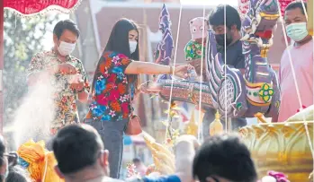  ?? VARUTH HIRUNYATHE­B ?? People pour blessed water into a vessel as a way to make merit at the Kwan Riam market along Saen Saep canal in Min Buri district.