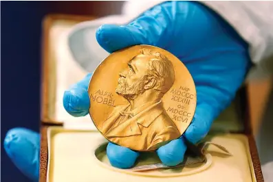 ?? Associated Press ?? A national library employee shows a gold Nobel Prize medal in Bogota, Colombia. The Nobels, with new winners announced this week, often concentrat­e on unheralded, methodical, basic science.