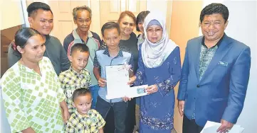  ??  ?? Fatimah (second right) holding Merlin’s identity card while Merlin (on Fatimah’s right) is seen holding his birth certificat­e at Fatimah’s office yesterday. Also seen are Marjina (left), Jasni (right), Manjeet (back row, third left) and Merlin’s family...