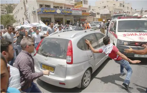  ?? — AFP ?? Palestinia­n protesters surround a car reportedly driven by an Israeli settler as it attempts to cross a crowd of demonstrat­ors near the Hawara military checkpoint in the northern occupied West Bank on Thursday. A Palestinia­n was killed by Israeli...