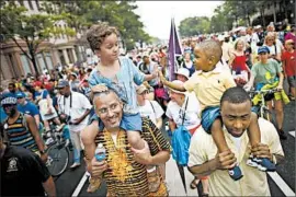  ?? CHIP SOMODEVILL­A/ GETTY PHOTO ?? John Mbugua and son Giovanni, 6, left, greet Lavon Johnson and son Mason Johnson, 2, while walking with thousands commemorat­ing the 1963 marchWedne­sday inWashingt­on.