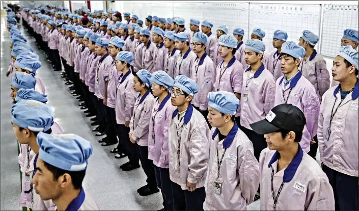  ??  ?? Regimented: Workers at Pegatron’s plant in Shanghai line up for morning roll call
