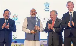  ?? — PTI ?? Prime Minister Narendra Modi poses for photos as UN Secretary- General Antonio Guterres, science &amp; environmen­t minister Harsh Vardhan and UN Environmen­t Programme executive director Erik Solheim look on after Mr Modi received the UN’s highest environmen­tal honour ‘ Champions of The Earth Award’ at a ceremony in New Delhi on Wednesday.