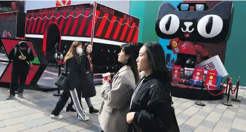  ?? NG HAN GUAN / THE ASSOCIATED PRESS ?? Shoppers in Beijing walk by a promotion by Alibaba for the upcoming 10th Singles Day event. Begun in the ’90s as a version of Valentine’s Day for people without romantic partners to splurge on themselves, the day has grown into the world’s biggest e-commerce event.