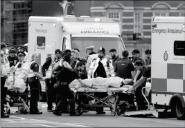  ?? ASSOCIATED PRESS ?? EMERGENCY SERVICES TRANSPORT AN INJURED PERSON to an ambulance close to the Houses of Parliament in London on Wednesday.