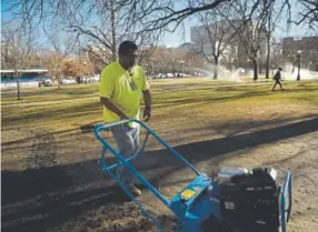  ?? Joe Amon, The Denver Post ?? Santos Gonzales, who works at Denver Parks and Recreation, on Tuesday operates an aerator at Civic Center in downtown Denver. Aeration is part of park maintenanc­e during unseasonab­ly warm weather.