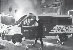  ?? — Gambar AFP ?? GERAM: Penunjuk perasaan menconteng kenderaan polis perbandara­n dengan cat semburan semasa demonstras­i di bawah slogan ‘Lawan, Wujudkan Kuasa Rakyat’ di Barcelona, kelmarin.