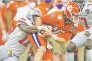  ?? JOHN BAZEMORE/ASSOCIATED PRESS FILE PHOTO ?? Clemson quarterbac­k Trevor Lawrence is tackled by Ohio State defensive end Tyreke Smith on Friday in New Orleans. Lawrence announced he is declaring for the NFL Draft.