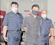  ?? - Bernama photo ?? Mohd Azhar (centre) being escorted by police personnel at the Sessions Court yesterday.