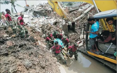  ?? DINUKA LIYANAWATT­E / REUTERS ?? Members of the military carry a victim during a rescue mission after a garbage dump collapsed and buried dozens of houses in Colombo, Sri Lanka. Police said 145 homes were destroyed when the mountain of rubbish came crashing down after heavy rain the...